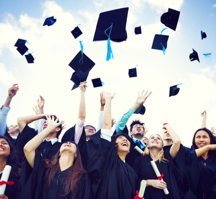 a photo of graduates of higher education in togas tossing their caps in the air amid a blue sky