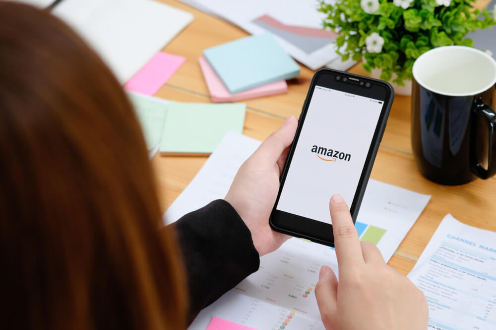 a woman looking at a phone in her hand and thinking about Amazon Storefronts