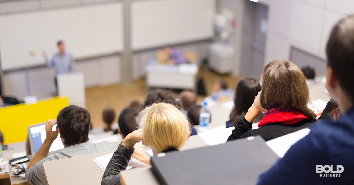 a photo of a classroom full of students listening to a teacher in front talk about the topic of states ranked by education quality