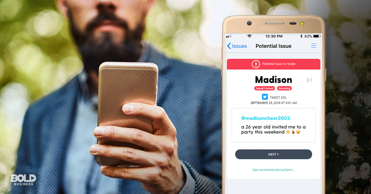 a photo of a man in a business suit holding up his phone, looking at a Bark App notification that popped on the screen