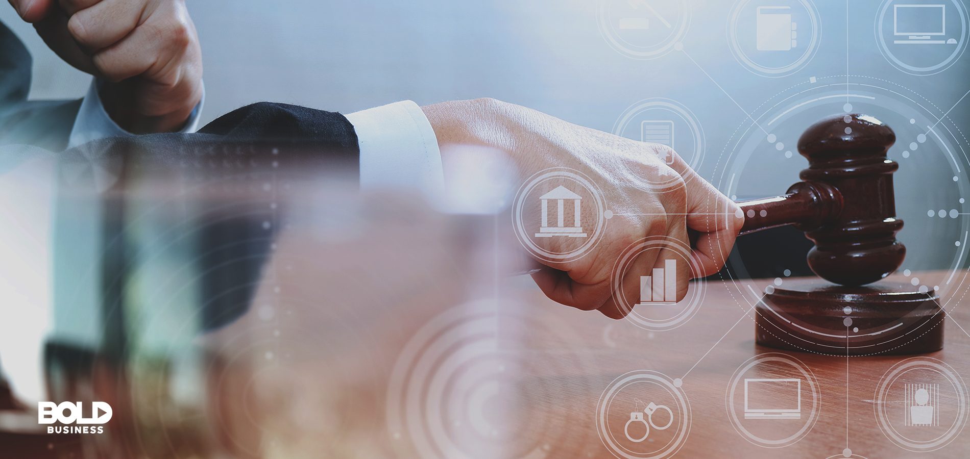 Hand holding a gavel surrounded by digital icons to signify digital justice.