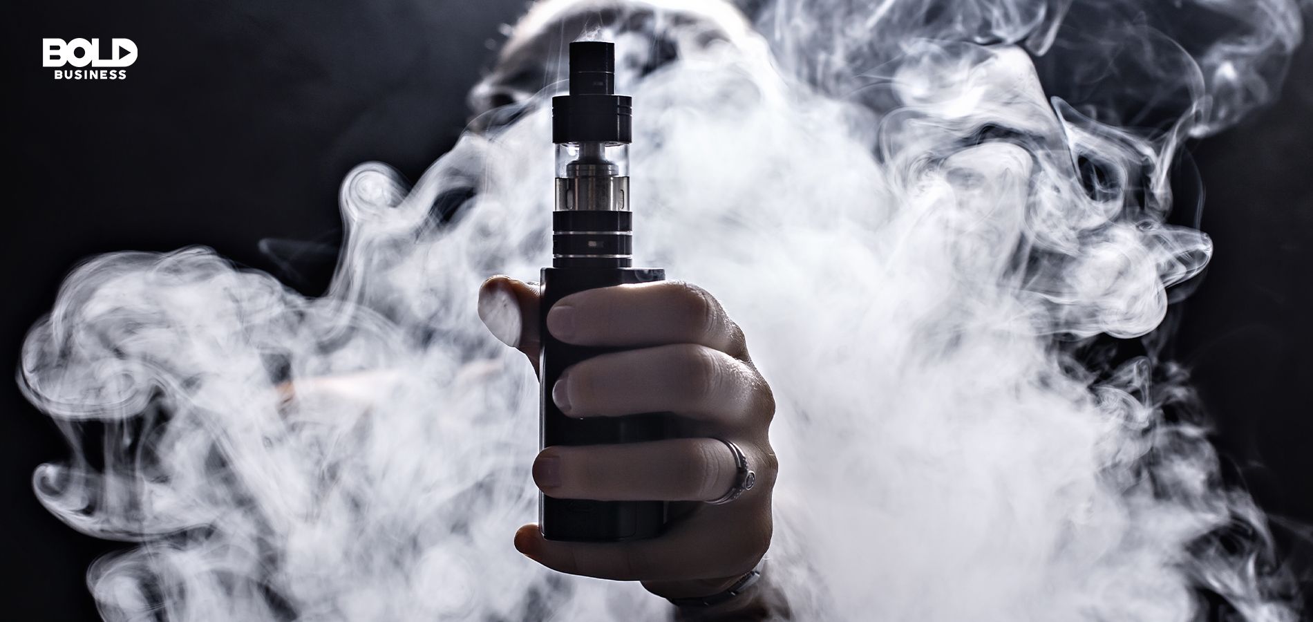 Vaping smoke behind hand holding vape.