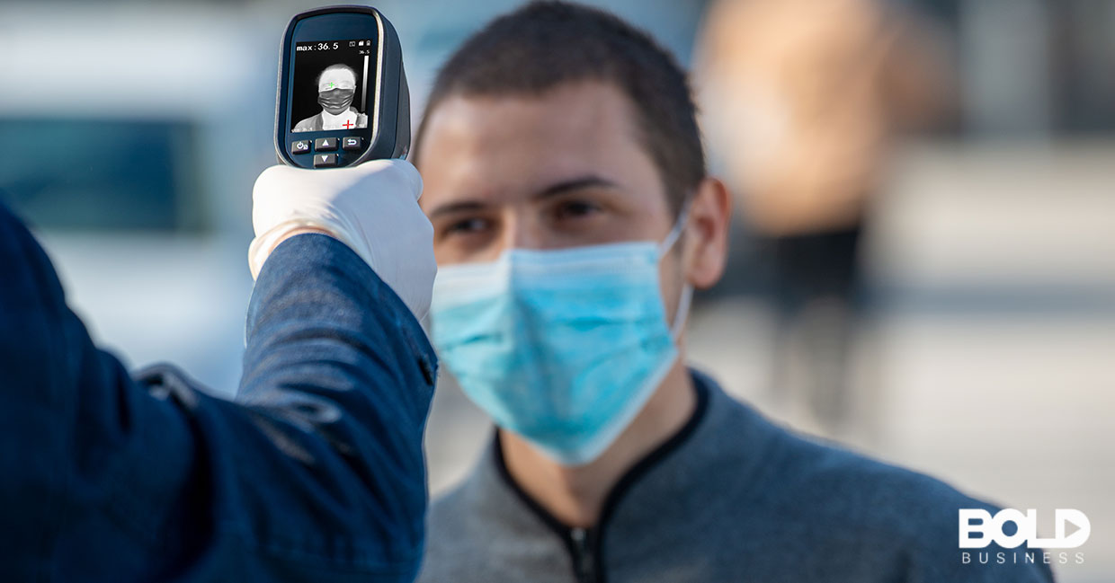 Someone in a face mask getting their temperature checked