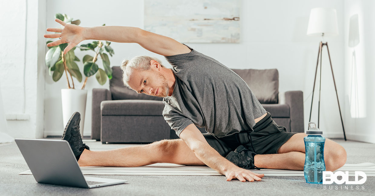 A dude performing stretches before his laptop
