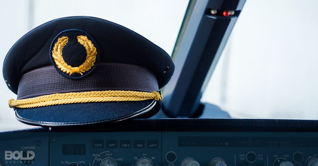 A pilot's cap resting on the dashboard of a cockpit