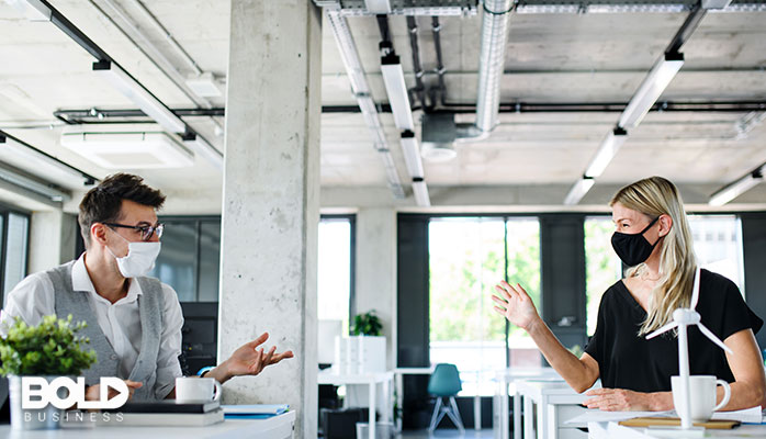 A pair of workmates socially distanced in their office