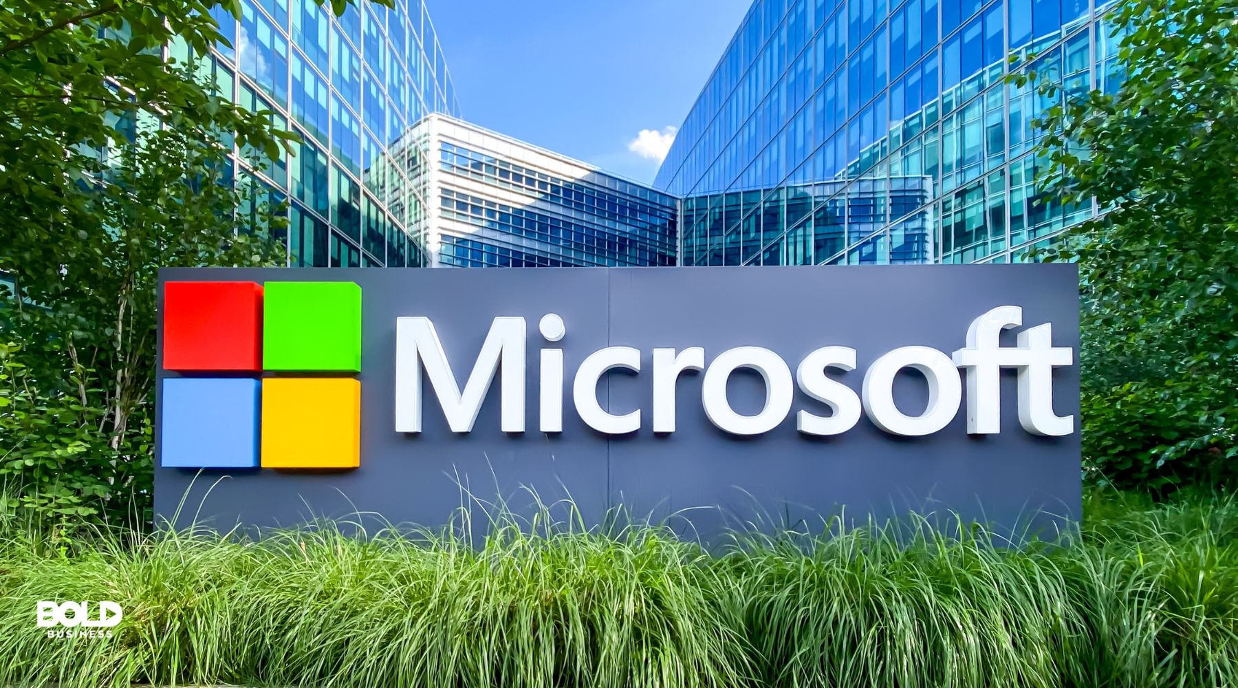 Microsoft sign in front of a modern office building surrounded by greenery.